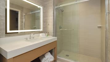 Ein modernes Badezimmer mit großem Spiegel, Waschbecken in Weiß und einer Duschkabine.