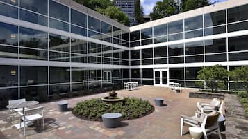 Un edificio moderno con un patio que cuenta con asientos exteriores y una fuente de agua.
