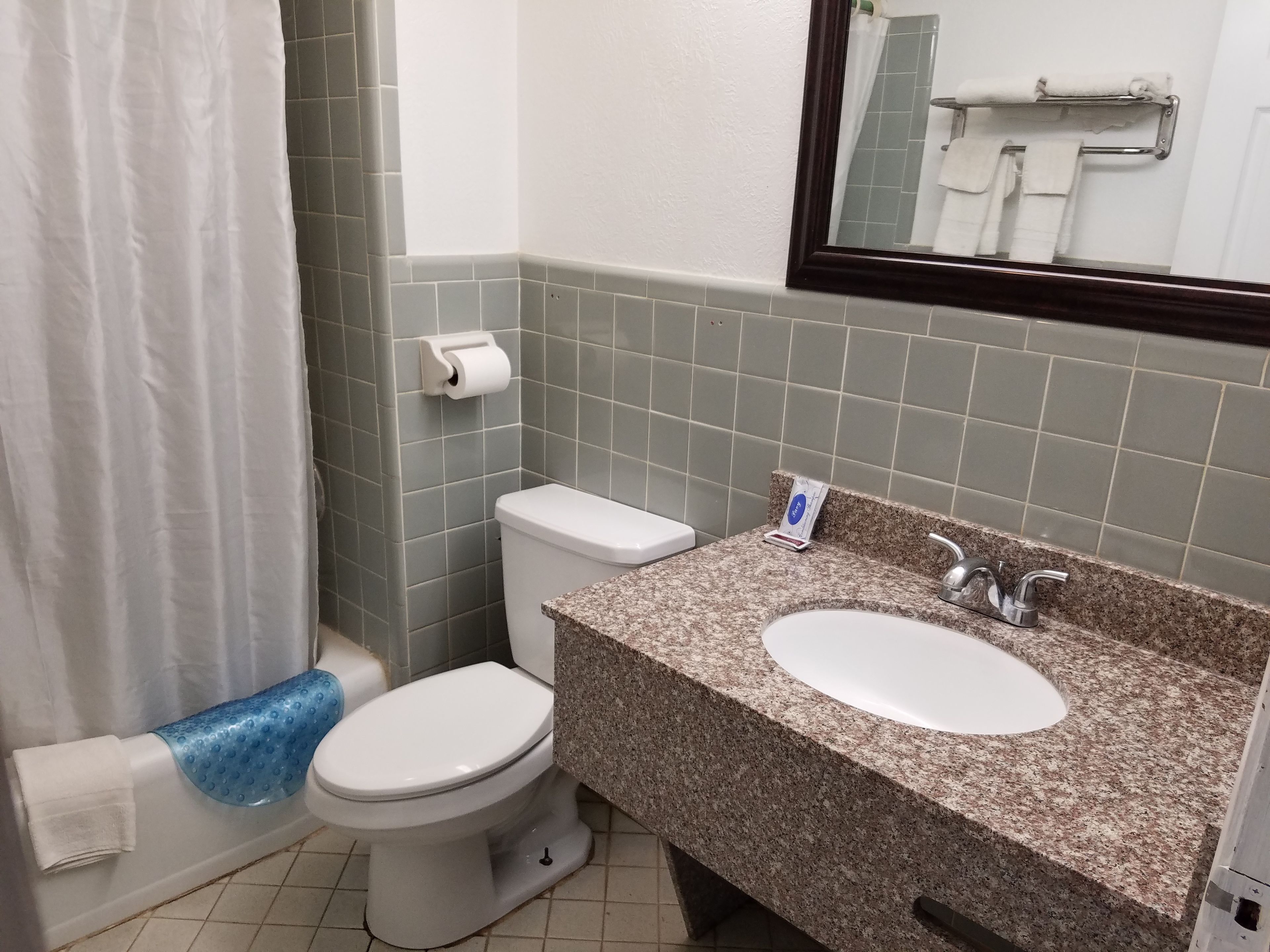 A bathroom with a toilet, sink, and shower curtain.