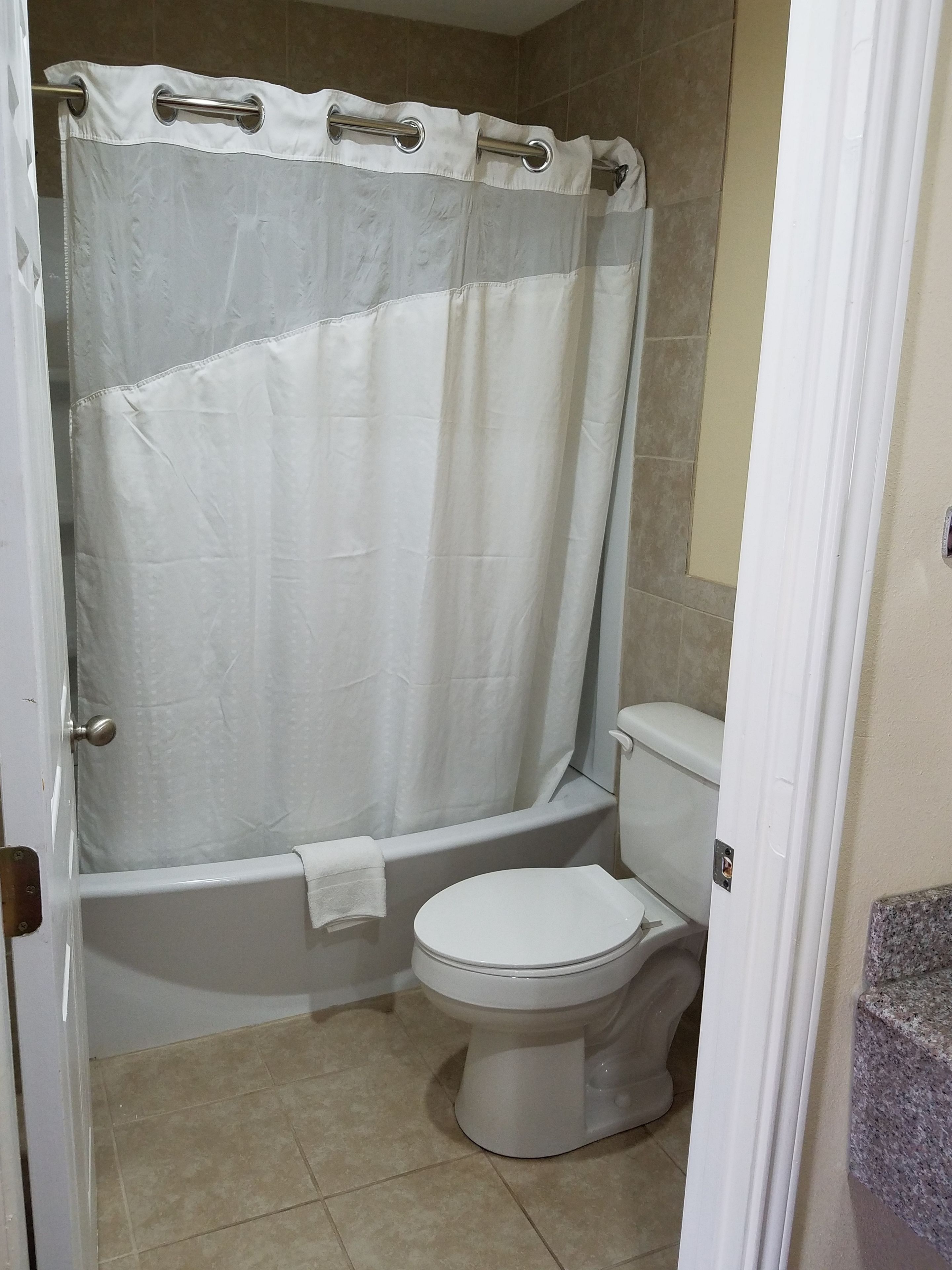 Un baño con cortina de ducha, bañera y retrete.