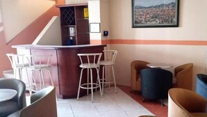 A hotel lobby with a bar area, seating arrangements, and a painting on the wall.
