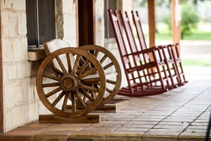 Wooden wheels and a wooden bench outside a building with a tiled floor. - Gruene Cottages (New Braunfels)