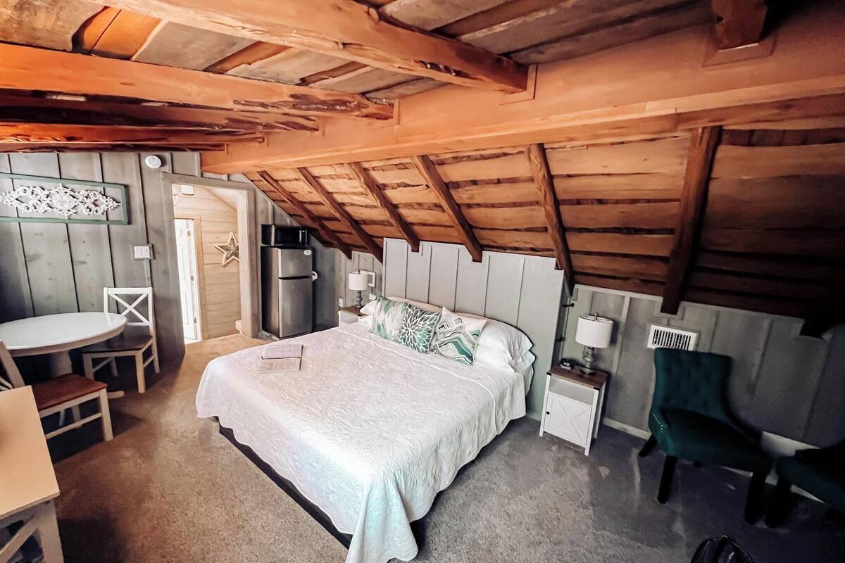 A cozy bedroom with a bed, bedside tables, a desk, and a chair.