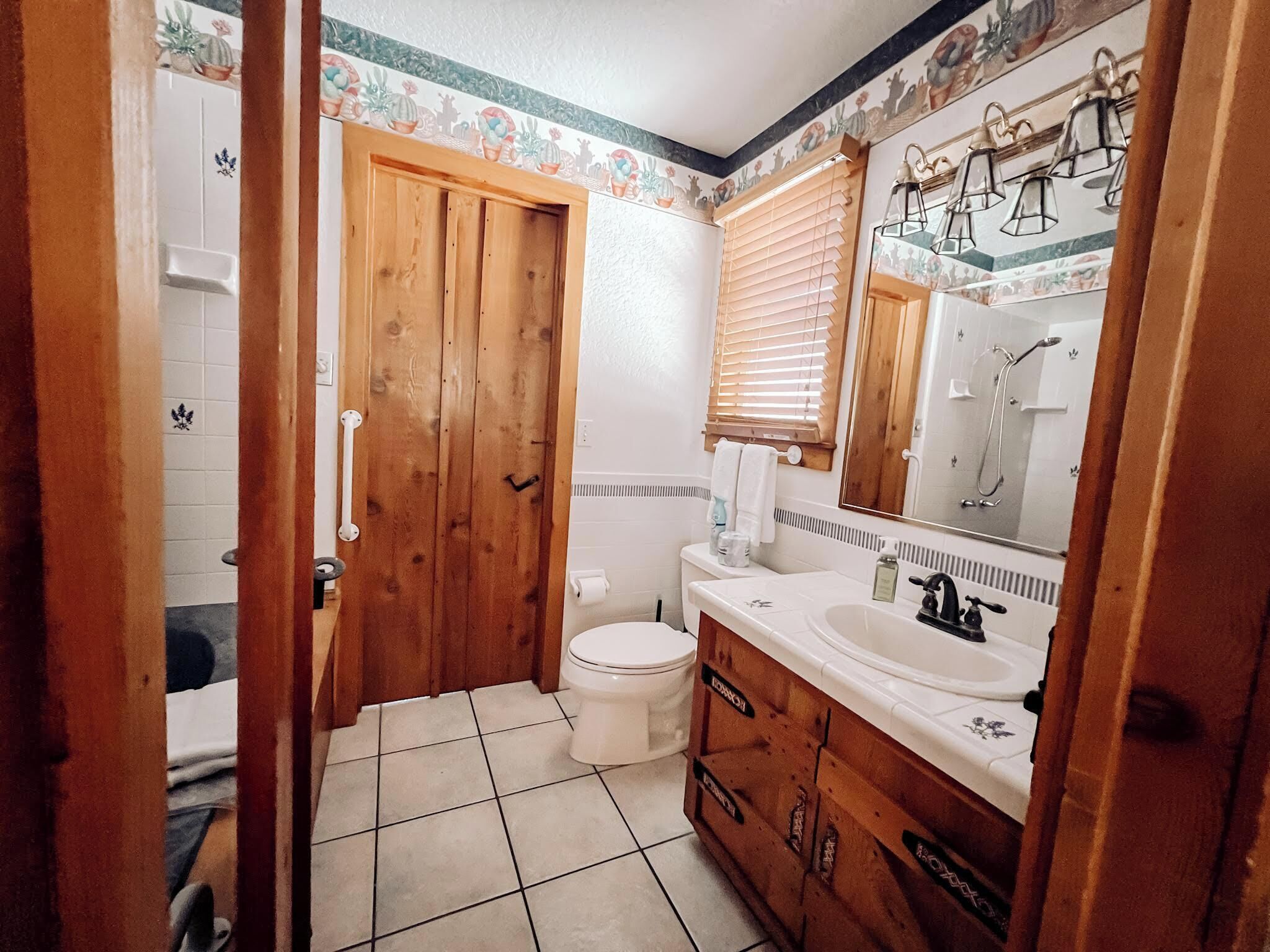 Et badeværelse med en trædør, toilet i hvidt og et spejl over vasken.