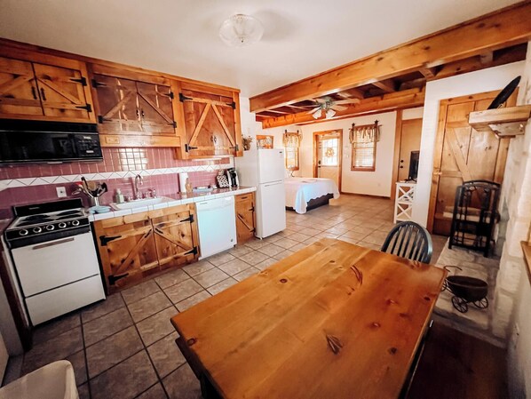 A compact kitchen with wooden cabinets, a stove, and a refrigerator. - Gruene Cottages (New Braunfels)