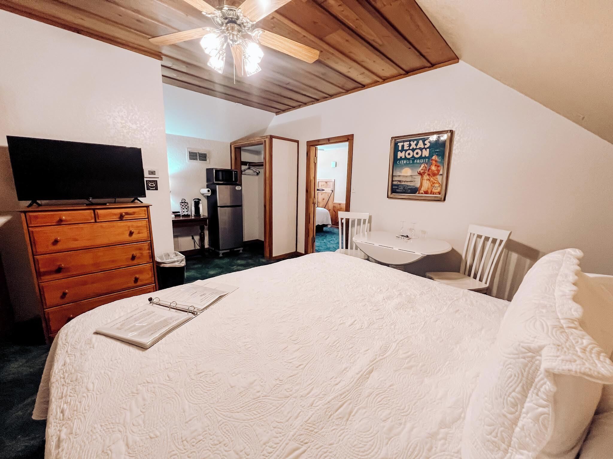 A bedroom with a bed, dresser, TV, and a poster on the wall.