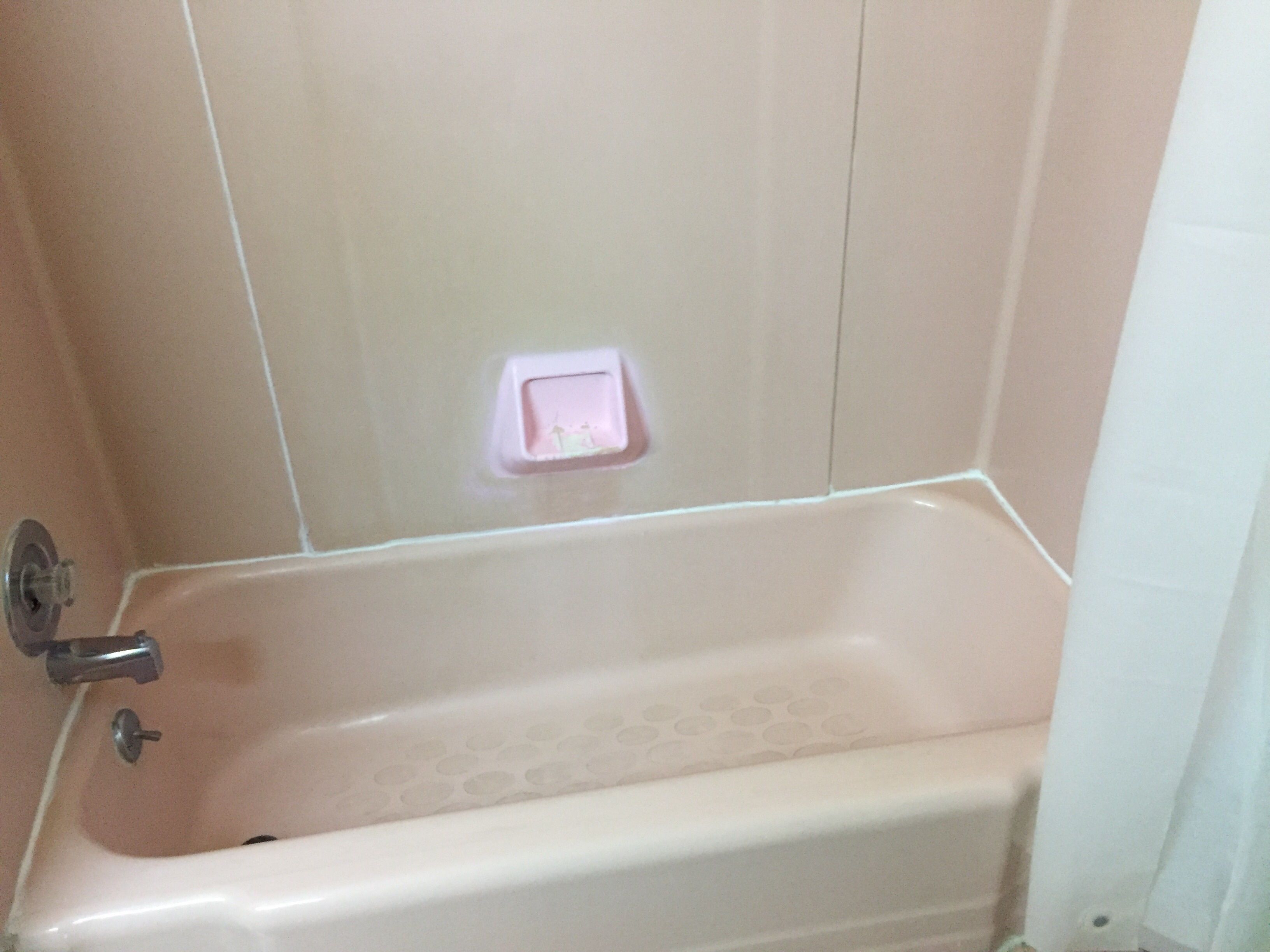 A bathtub with a faucet and a soap dish on the wall.