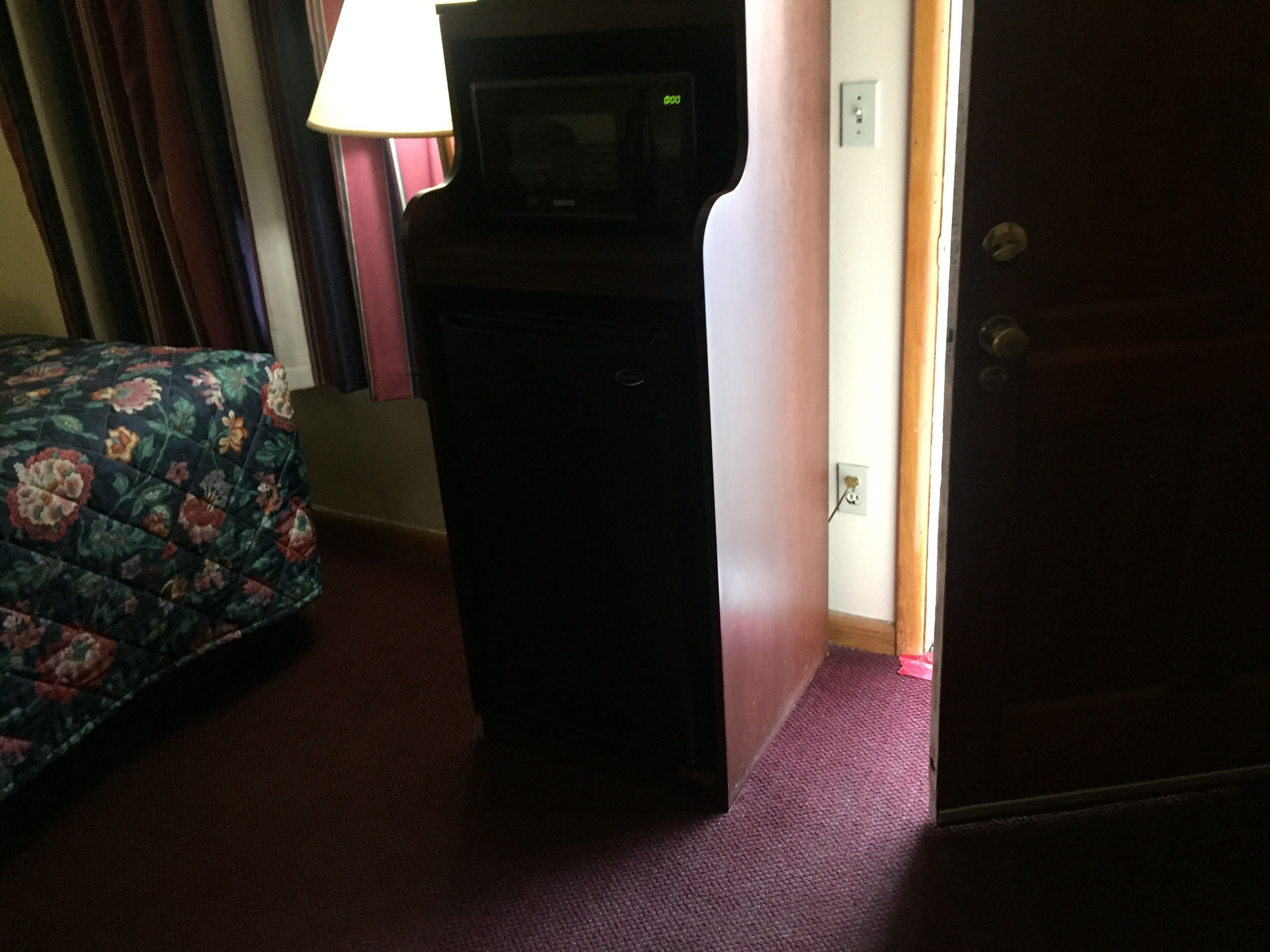 A hotel room with a bed, a desk, and a lamp.