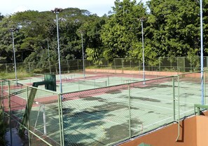 A tennis court surrounded by a green fence with trees in the background. - Viva Tambor Villas (Paquera)