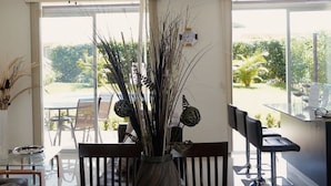 A dining area with a table, chairs, and a vase with decorative branches. - Viva Tambor Villas (Paquera)