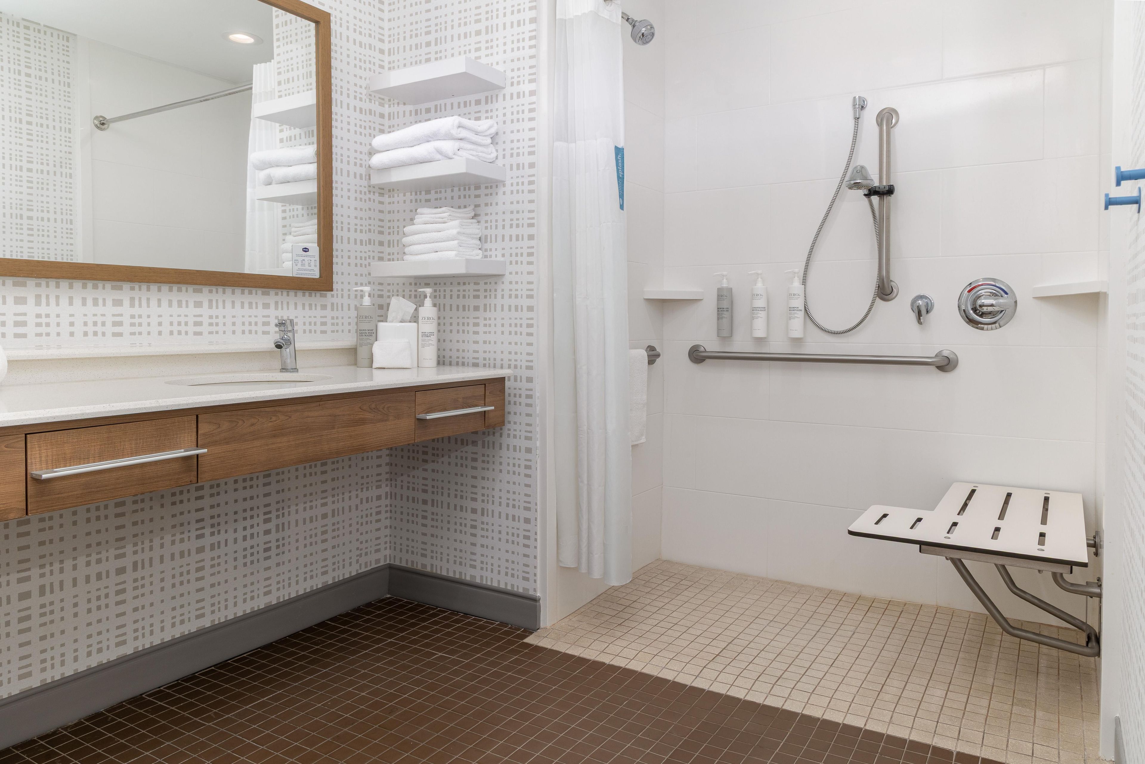 Un baño moderno con ducha, lavabo con espejo e inodoro.