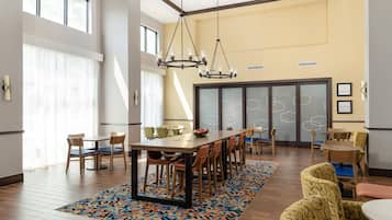 Uma sala de jantar espaçosa com uma mesa grande, várias cadeiras e um tapete estampado.