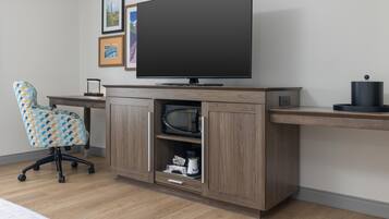 A modern office setup with a flat-screen TV, a patterned office chair, and a wooden desk with a shelf.