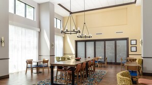 A spacious dining area with a large table, multiple chairs, and a patterned rug.