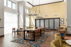A spacious dining area with a large table, multiple chairs, and a patterned rug.