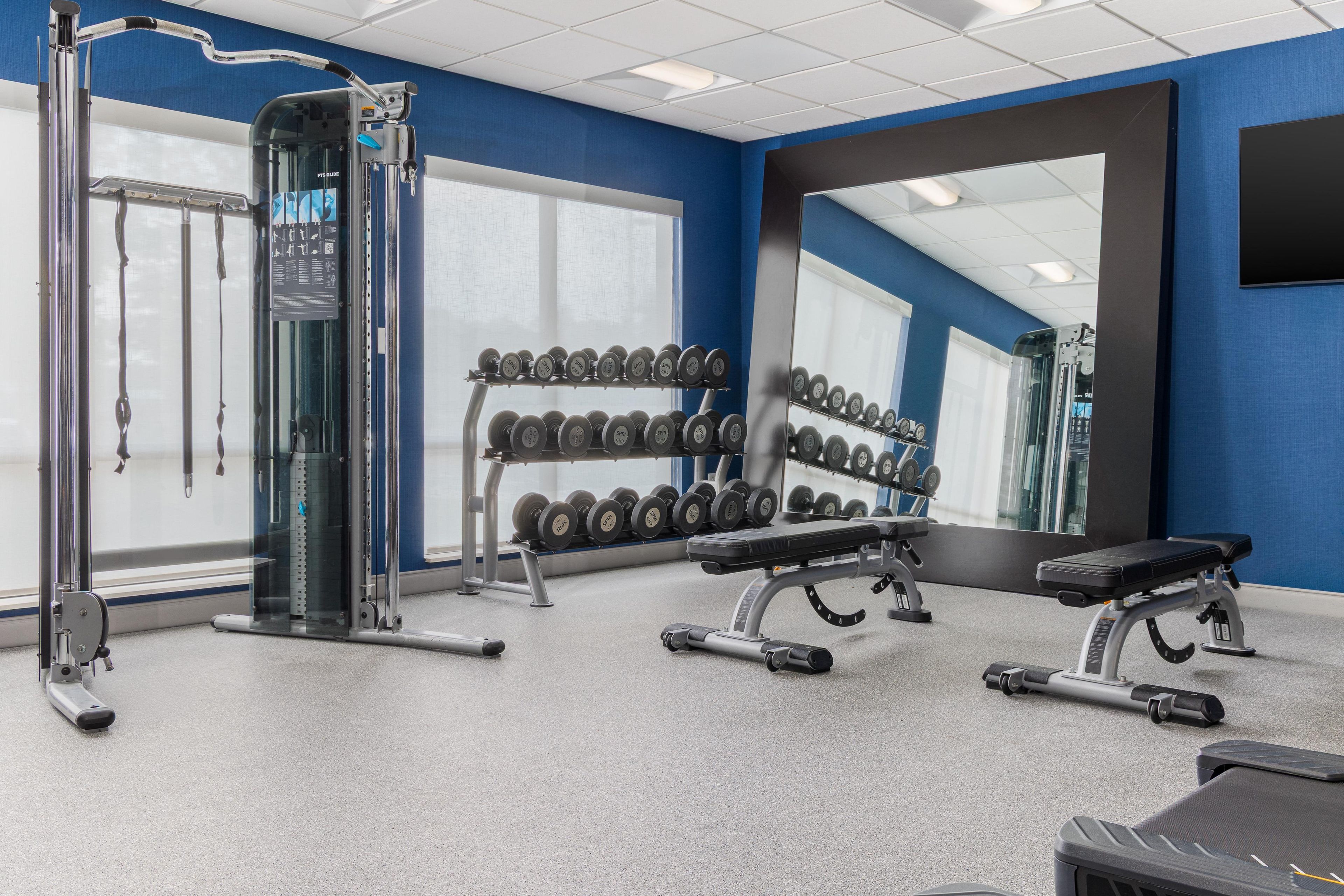 A gym with weightlifting equipment, dumbbells, and exercise machines.