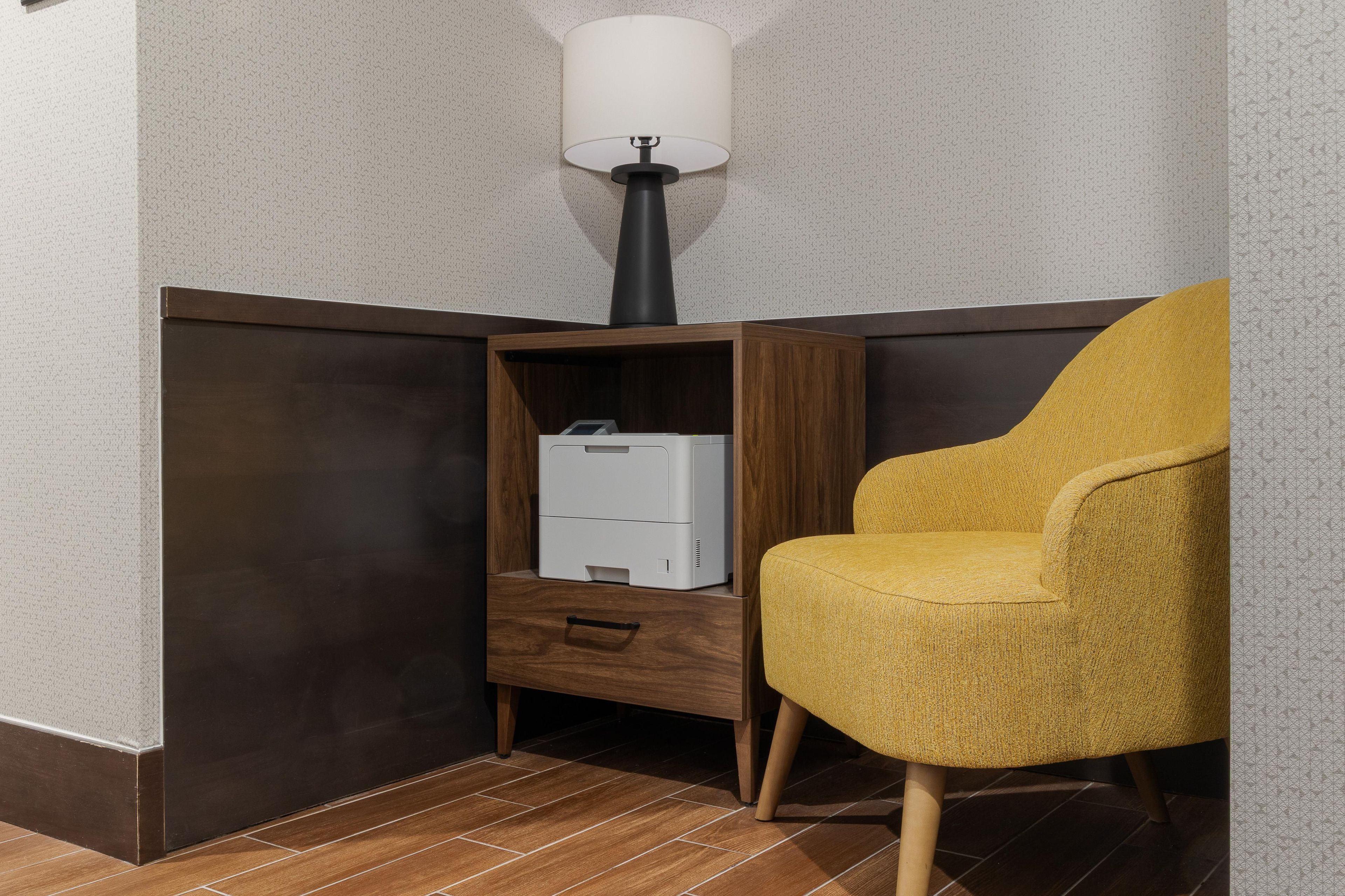 A corner room with a wooden cabinet, a white printer, and a yellow armchair.