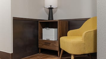 A corner room with a wooden cabinet, a white printer, and a yellow armchair.