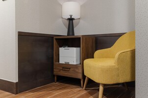 Una habitación de esquina con un mueble de madera, una impresora blanca y un sillón amarillo.
