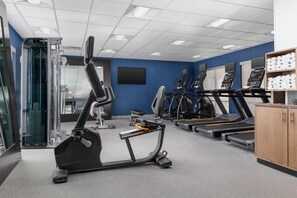 Un gimnasio con equipos de ejercicio variados, incluyendo cintas de correr y una máquina elíptica.