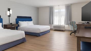A hotel room with two beds, a desk with a television, and a window with curtains.