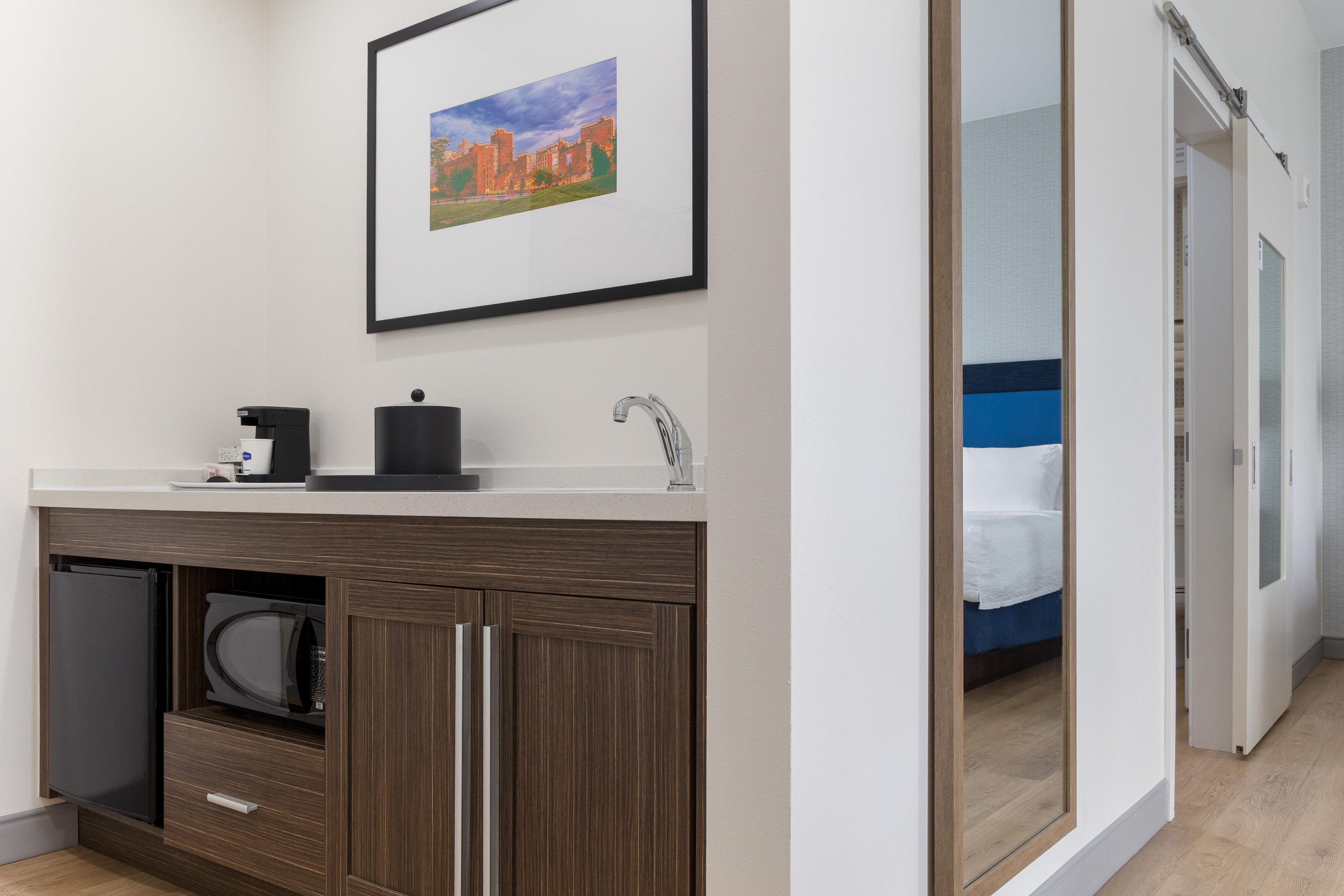 Ein modernes Badezimmer mit Waschbecken, einer Kaffeemaschine und einem gerahmten Bild an der Wand.
