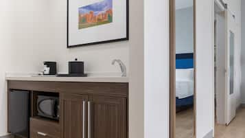 Ein modernes Badezimmer mit Waschbecken, einer Kaffeemaschine und einem gerahmten Bild an der Wand.
