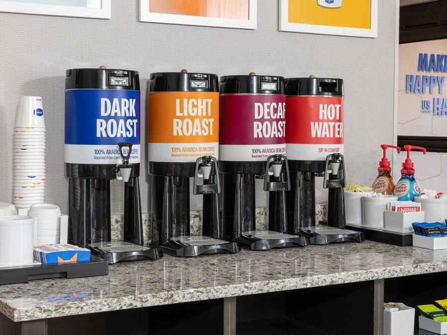 A coffee station with four dispensers labeled DARK ROAST, LIGHT ROAST, DECAF ROAST, and HOT WATER.