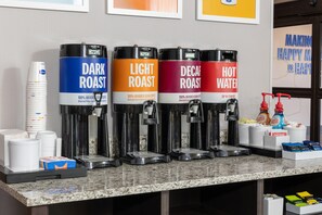A coffee station with four dispensers labeled DARK ROAST, LIGHT ROAST, DECAF ROAST, and HOT WATER.