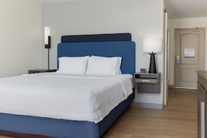 A hotel room with a bed, a nightstand, a lamp, and a door. - Hampton Inn & Suites Niles/Warren (Niles)