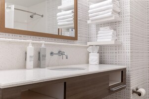 Un baño moderno con un espejo grande, un lavamanos y un perchero para toallas.