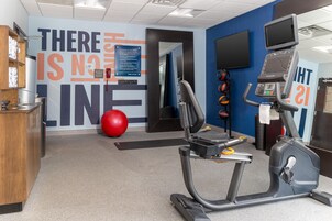 Un gimnasio con equipamiento de ejercicio, una pelota roja y decoración inspiradora en la pared.