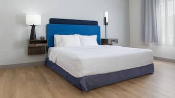 A hotel room with a bed, nightstands, a lamp, and a window with curtains.