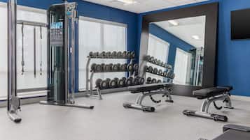 Un gimnasio con equipo de levantamiento de pesas, mancuernas y máquinas de ejercicio.