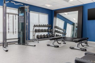 A gym with weightlifting equipment, dumbbells, and exercise machines.