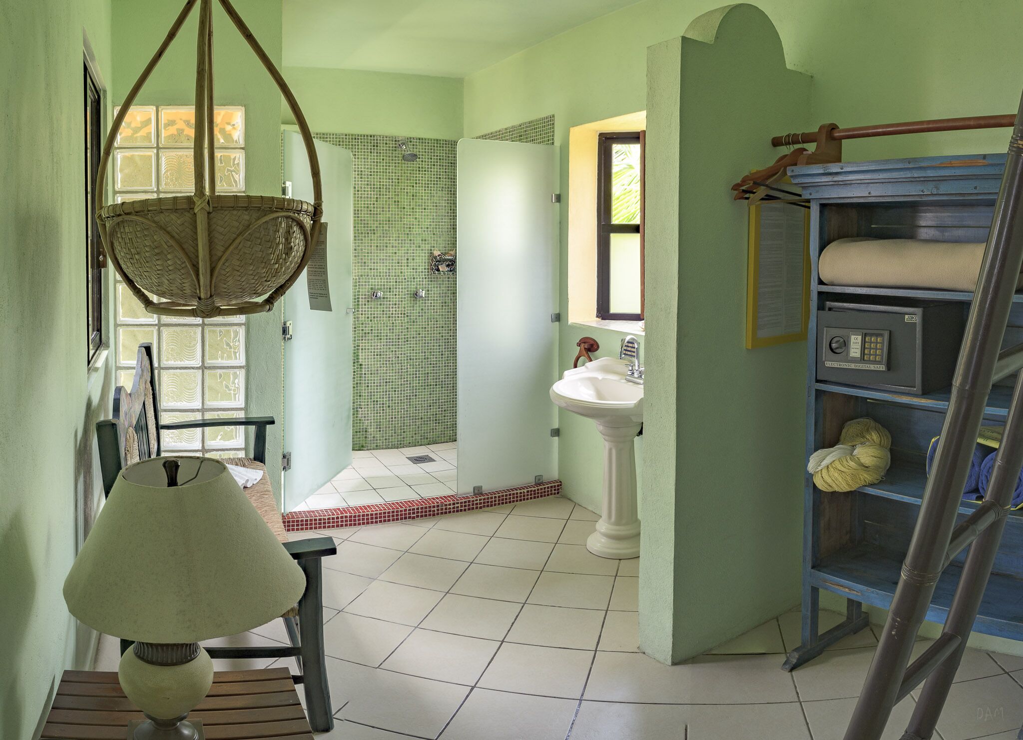 Ein Badezimmer mit Fliesenboden, einem Standwaschbecken, einer hängenden Körbotanne und einem Holzstuhl.