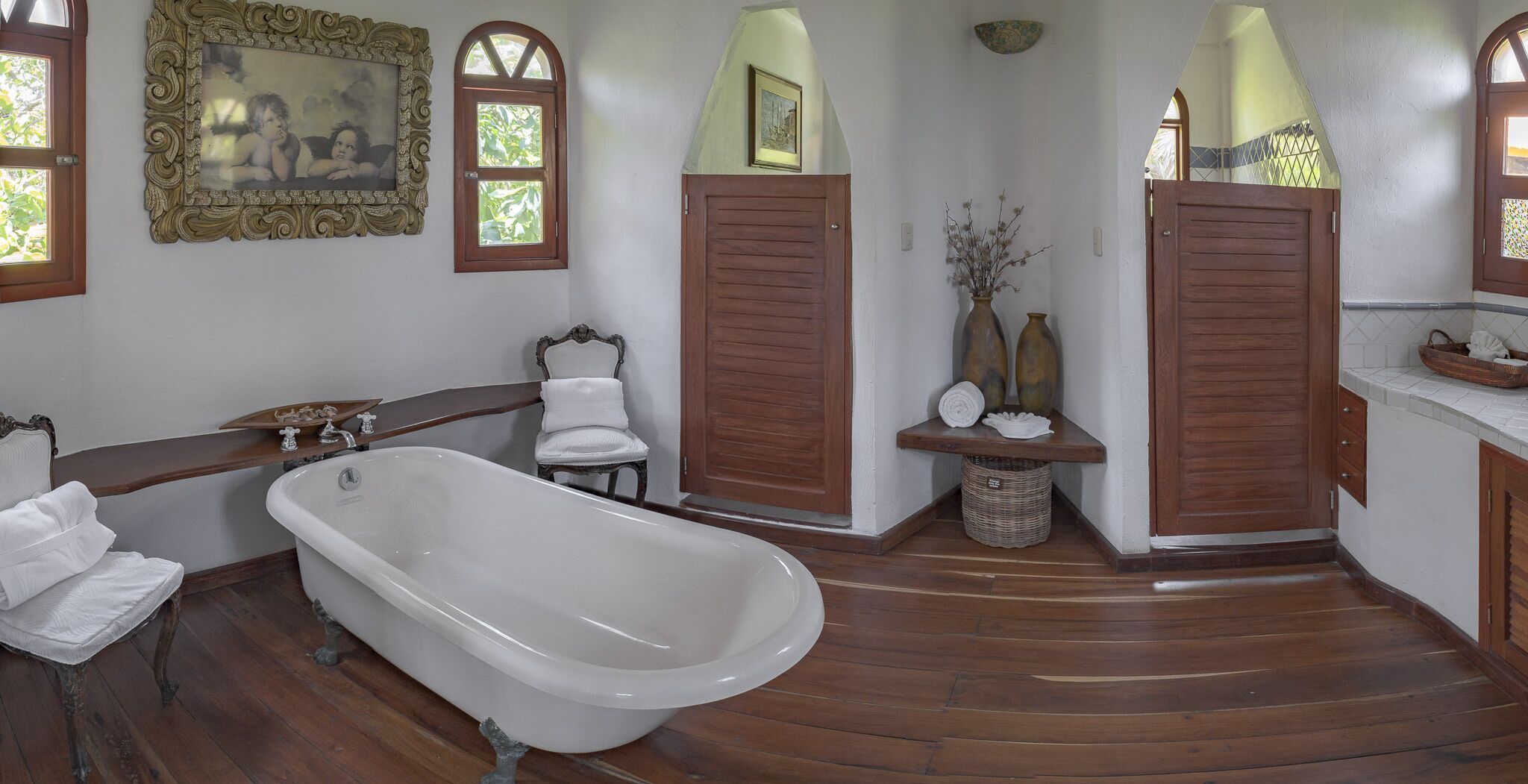 Un baño espacioso con una bañera independiente, puertas de madera y un tocador con espejo.