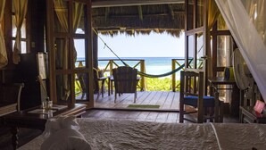 A room with a bed, a table with a bottle, and a view of the beach through an open door. - Nueva Vida de Ramiro (Tulum)