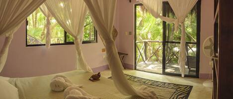 A bedroom with a bed, a window, and a view of greenery outside.