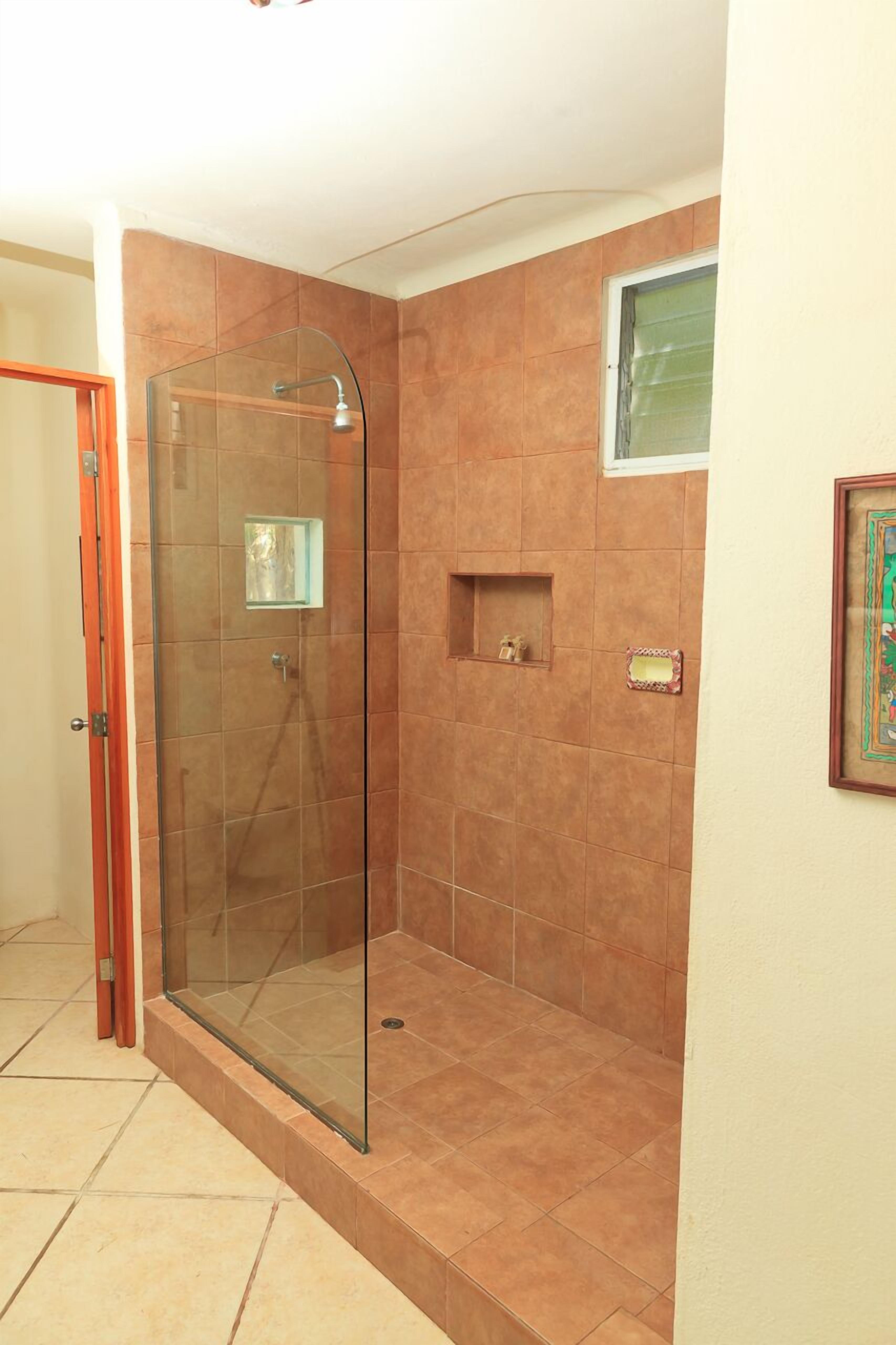 A shower with glass doors and a small shelf on the wall.