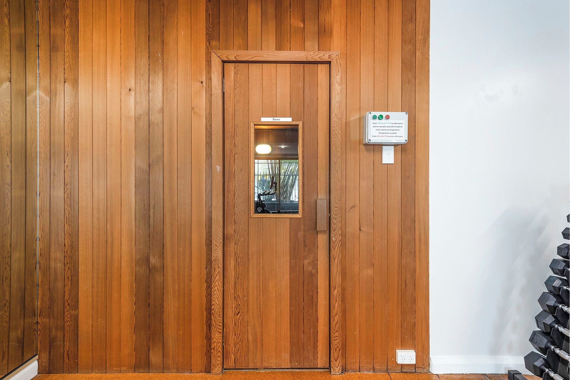 Una puerta de madera con un ventanal pequeño, una placa con nombre y un indicador de control de temperatura.