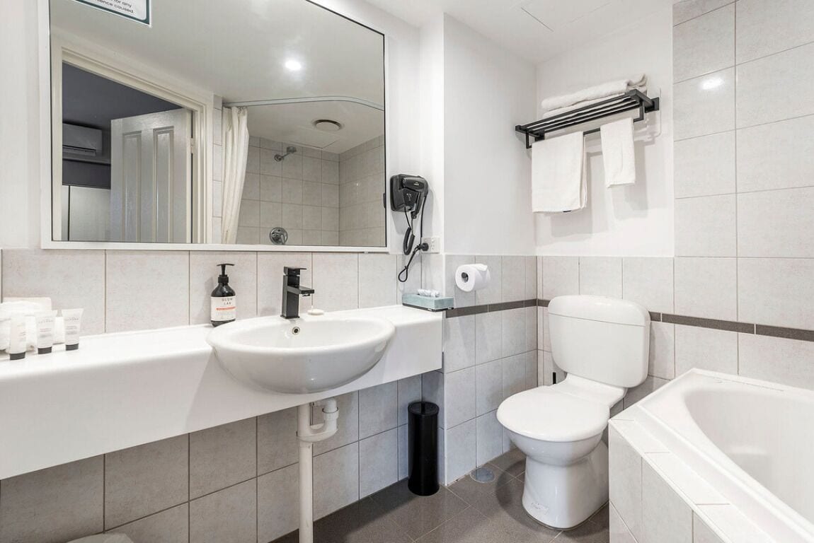 Un baño moderno con lavamanos, inodoro y bañera blancos.