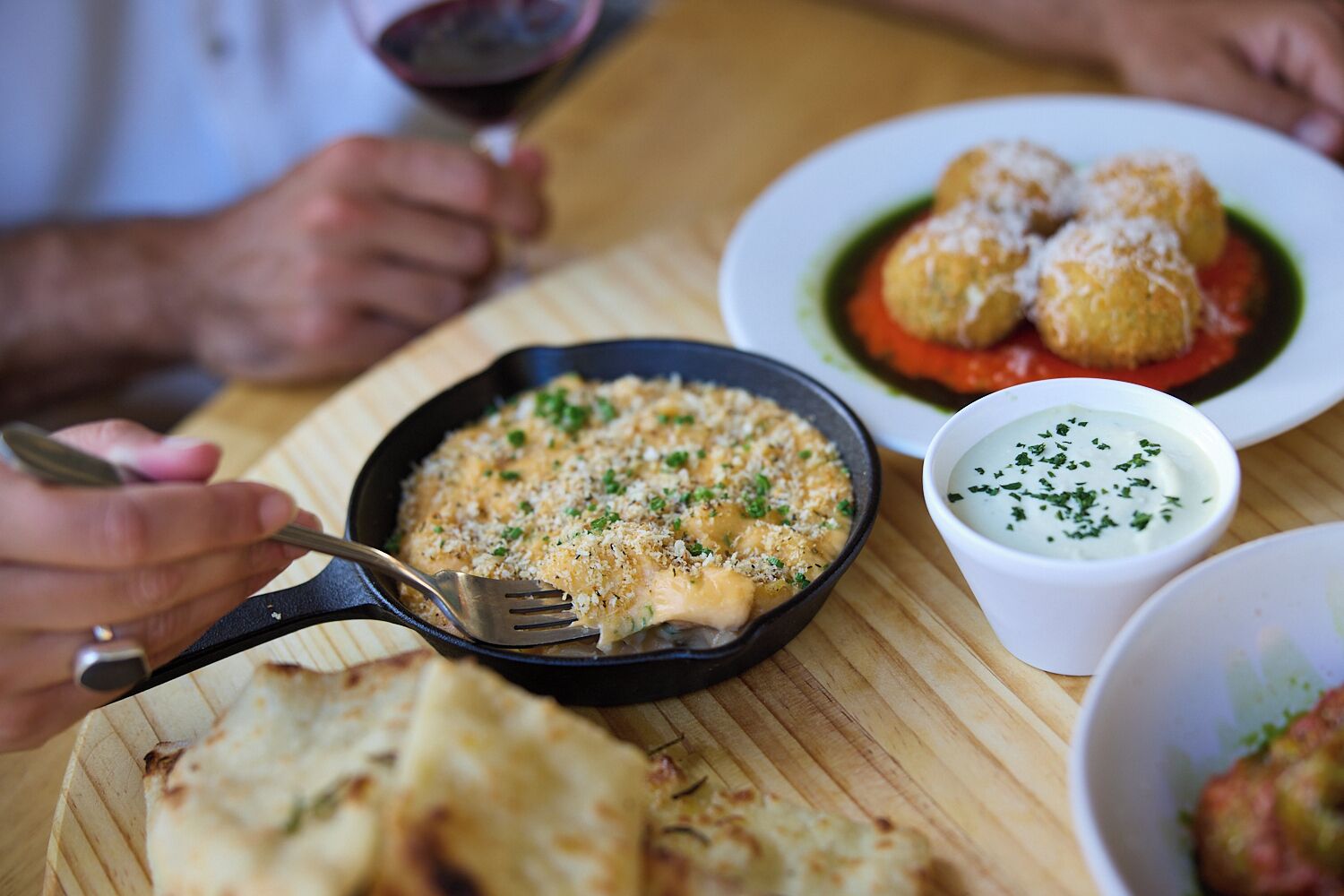 A dining table with a meal consisting of pasta, a bowl of sauce, and bread.