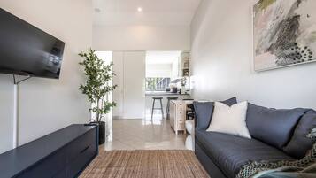 A modern living room with a flat-screen TV, a dark sofa, a coffee table, and a large abstract painting on the wall.
