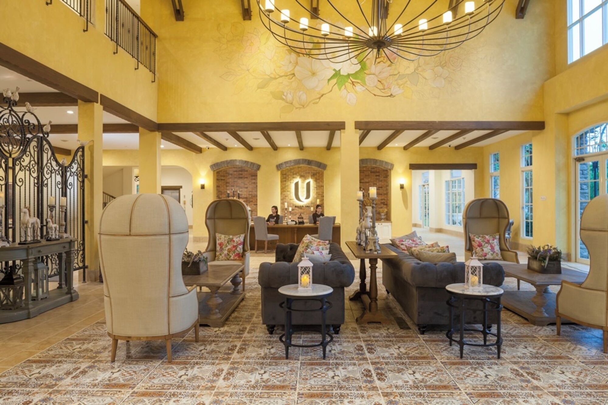 A spacious lobby with a high ceiling, a reception desk, and a seating area with armchairs and sofas.