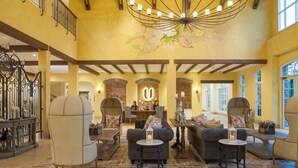 A spacious lobby with a high ceiling, a reception desk, and a seating area with armchairs and sofas. - U Khao Yai (Pak Chong)