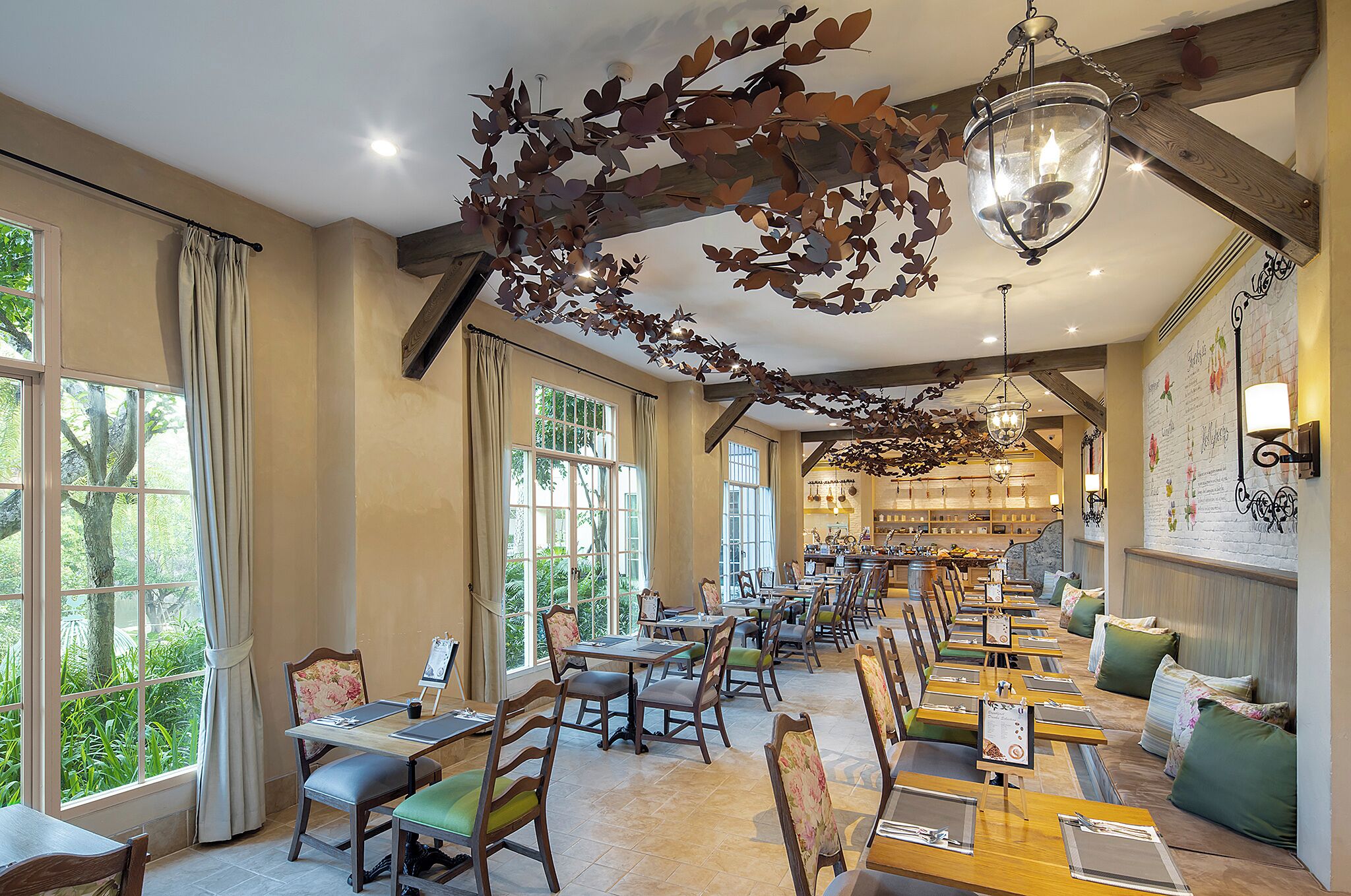 A restaurant with long tables, chairs, and hanging leaf decorations.