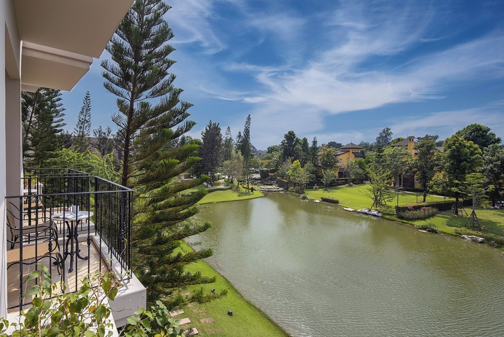 A balcony with a view of a lake, surrounded by trees and buildings.