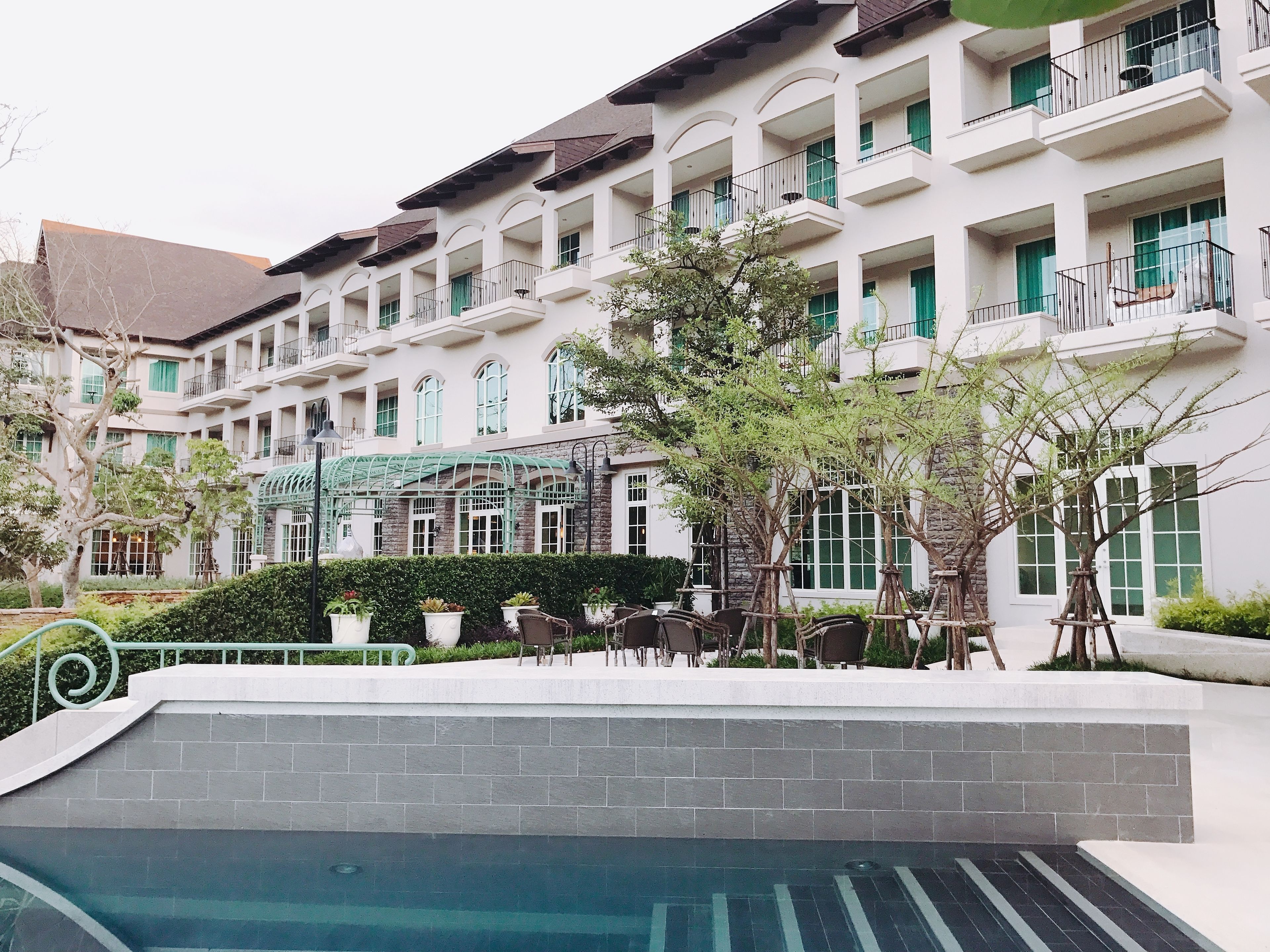 A multi-story hotel with balconies, a pool area, and outdoor seating.