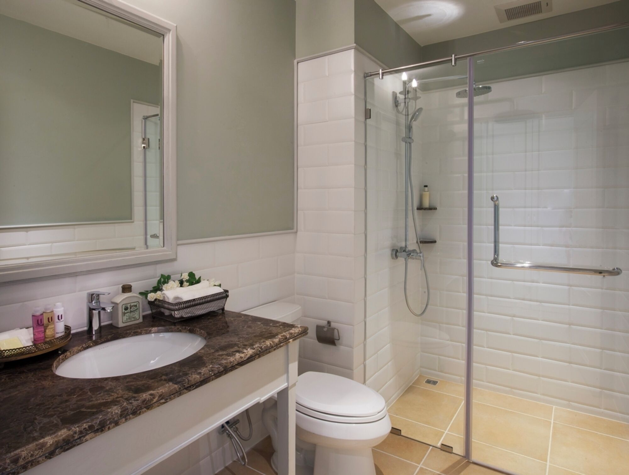 Un baño con lavamanos, inodoro y ducha con cerramiento de vidrio.
